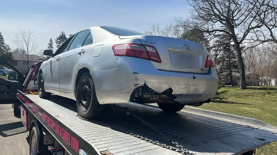 Silver Toyota Camry with rear-end damage loaded on a Camel Towing flatbed in St. Paul