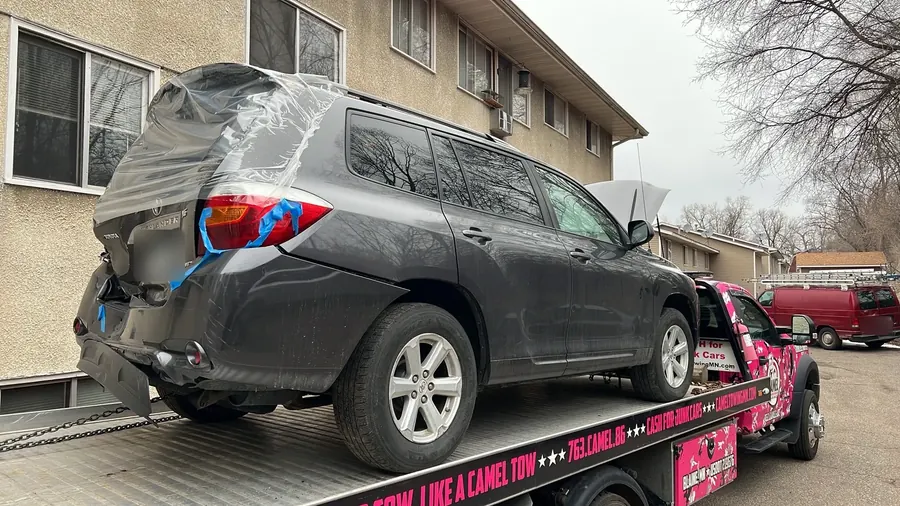 Damaged gray Toyota Highlander on a pink camo Camel Towing flatbed